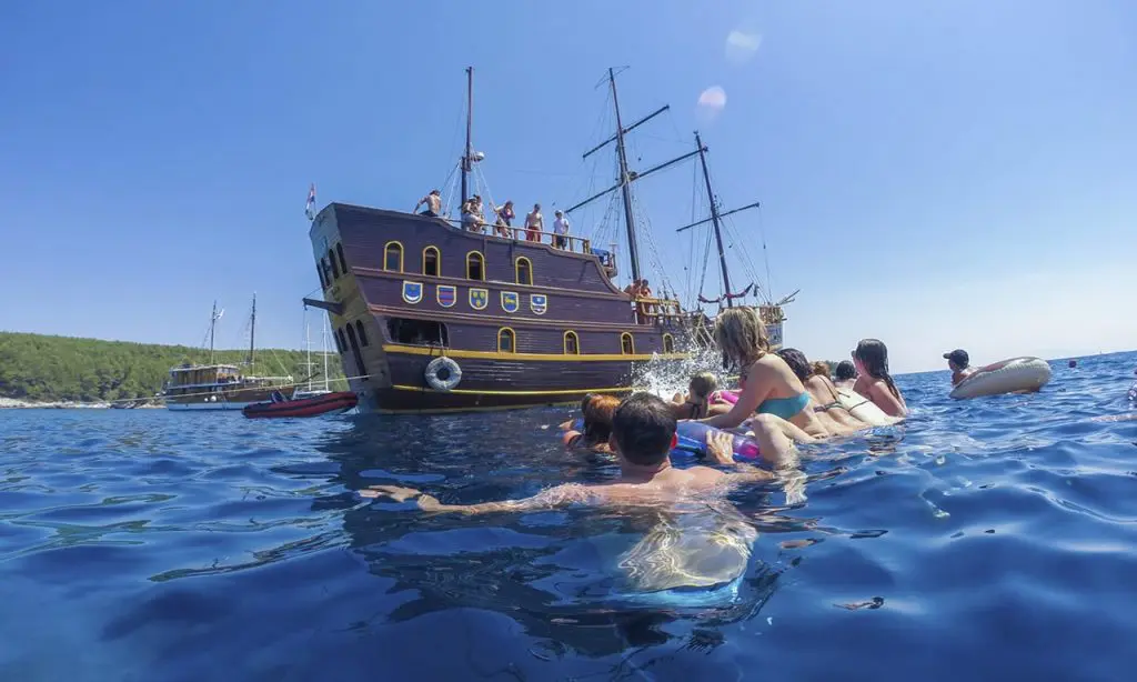 People swimming in Croatia's bay in front of yatch