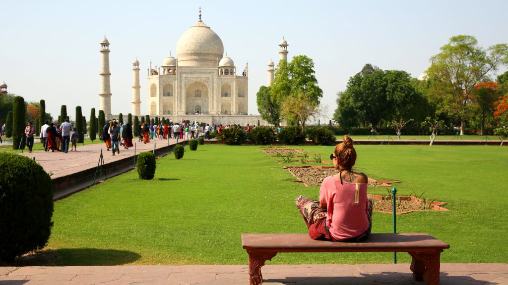 Caucasian woman sitting on bench and looking to Taj Mahal
