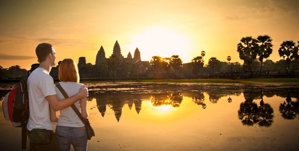 Couple at Angkor Wat temple complex in sunrice, near Siem Reap, Cambodia. Panoramic view.